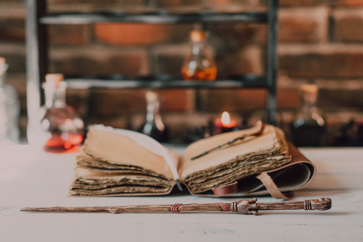 Close-up of a wooden wand and ancient spell book in a mystical, rustic environment.