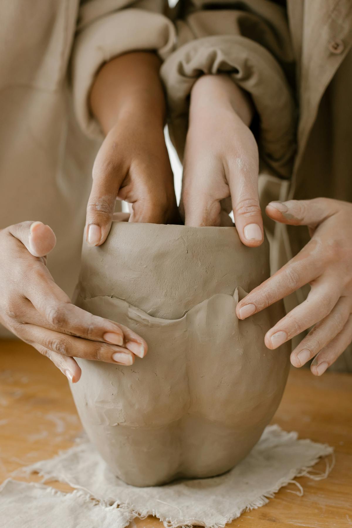 Close-up of hands molding a clay pot, showcasing artisan skills and craftsmanship.